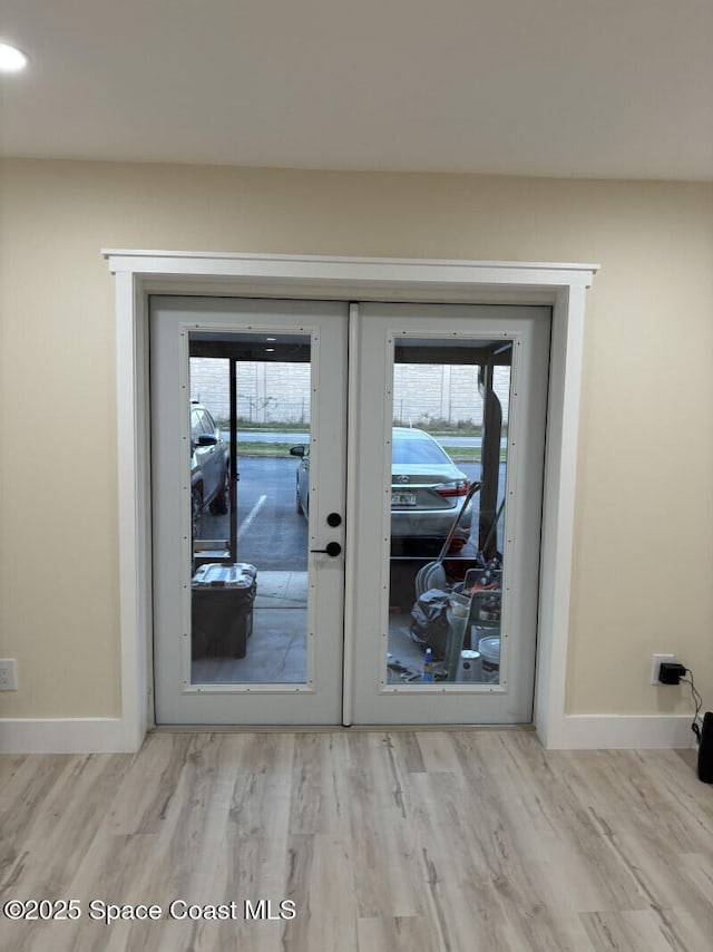 doorway featuring light wood-type flooring, baseboards, and french doors