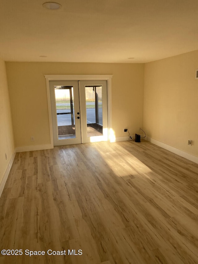 empty room featuring french doors, wood finished floors, and baseboards