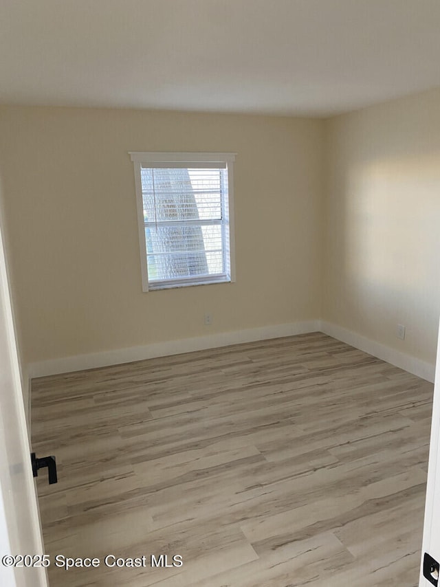 spare room featuring light wood-type flooring and baseboards