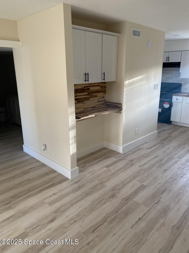 kitchen with visible vents, baseboards, white cabinets, decorative backsplash, and light wood finished floors