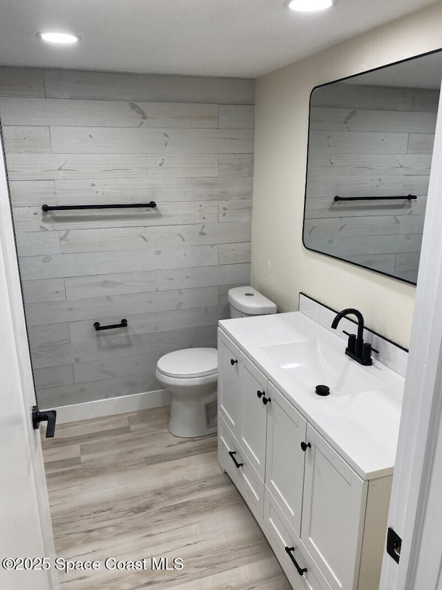 bathroom featuring recessed lighting, toilet, vanity, wood finished floors, and baseboards