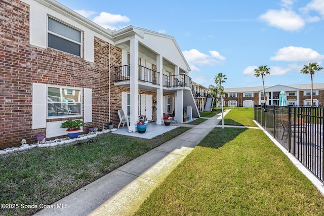 view of home's community with a patio area, fence, and a lawn