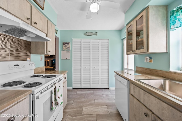 kitchen with white appliances, under cabinet range hood, glass insert cabinets, and light countertops