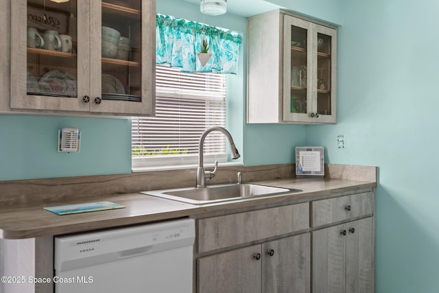 kitchen with white dishwasher, glass insert cabinets, light countertops, and a sink