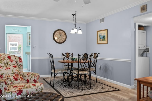 dining area featuring baseboards, visible vents, wood finished floors, crown molding, and stacked washing maching and dryer