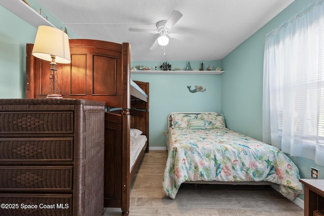 bedroom featuring baseboards, multiple windows, a ceiling fan, and wood finished floors