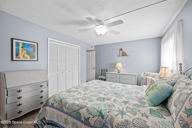 tiled bedroom featuring a closet, visible vents, ceiling fan, and a textured ceiling