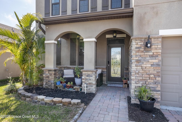 property entrance with stone siding, stucco siding, a porch, and a garage