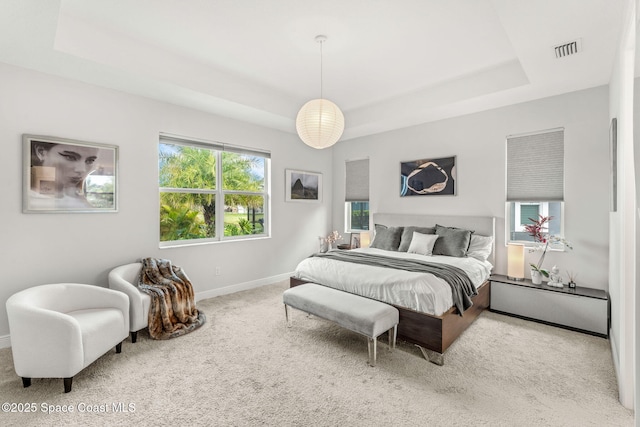 carpeted bedroom with baseboards, visible vents, and a tray ceiling