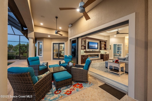 view of patio / terrace featuring glass enclosure, an outdoor living space, and a ceiling fan