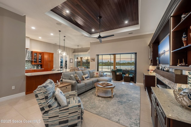 living area with wooden ceiling, a fireplace, baseboards, and a raised ceiling