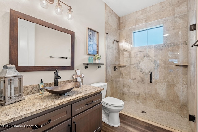 bathroom featuring vanity, a stall shower, wood finished floors, and toilet