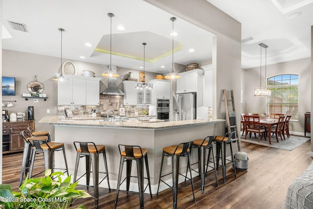 kitchen featuring a tray ceiling, appliances with stainless steel finishes, a peninsula, and visible vents