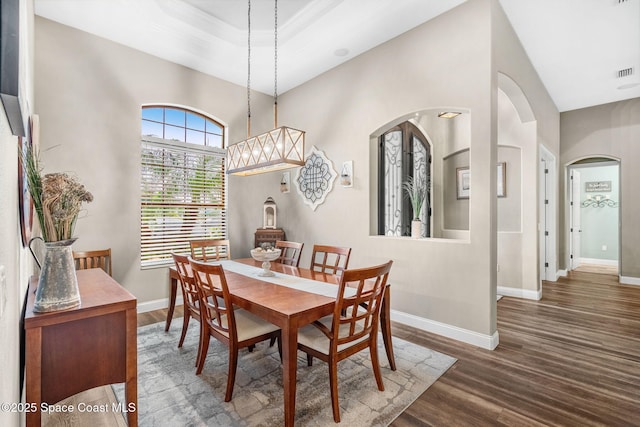 dining area featuring arched walkways, visible vents, baseboards, and wood finished floors