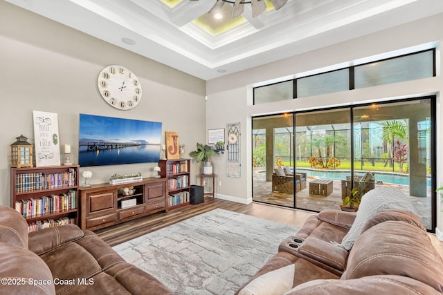 living area featuring crown molding, a towering ceiling, a sunroom, wood finished floors, and coffered ceiling