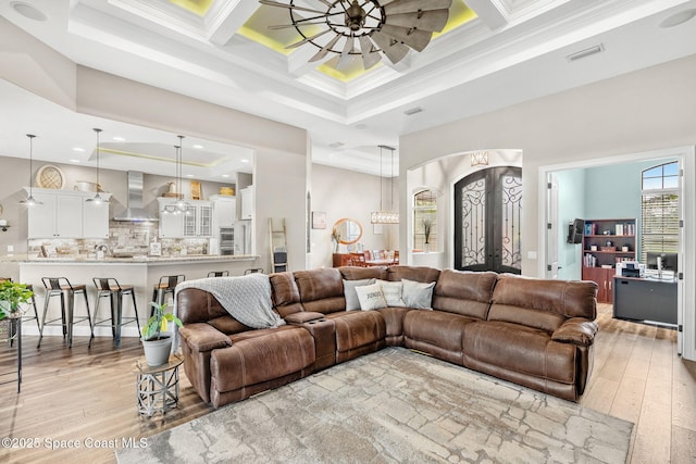 living area featuring arched walkways, french doors, ceiling fan, and light wood finished floors