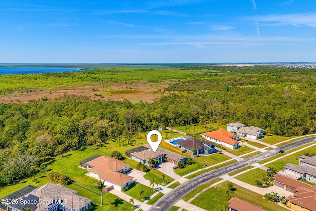 drone / aerial view featuring a water view, a wooded view, and a residential view