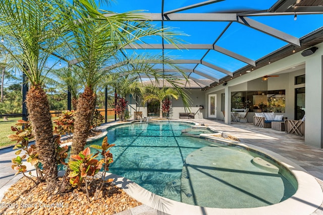 view of swimming pool with a lanai, a pool with connected hot tub, a ceiling fan, and a patio