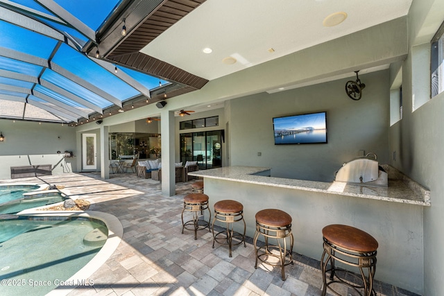 view of patio / terrace with a pool with connected hot tub, area for grilling, glass enclosure, a grill, and outdoor wet bar