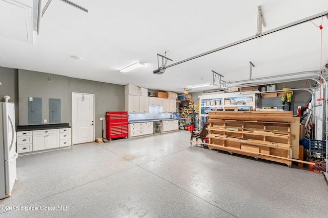 garage featuring a garage door opener, freestanding refrigerator, and electric panel