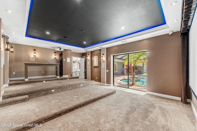 cinema room with carpet, a raised ceiling, and baseboards