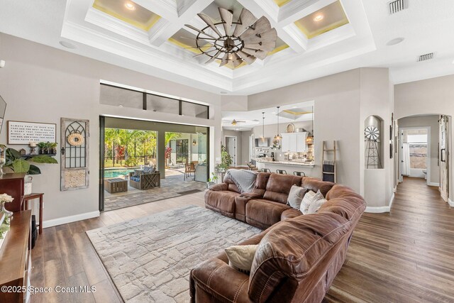 living room with ceiling fan, a high ceiling, visible vents, and ornamental molding