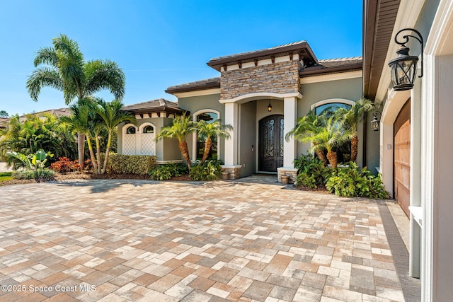 exterior space featuring stone siding, a tile roof, and stucco siding