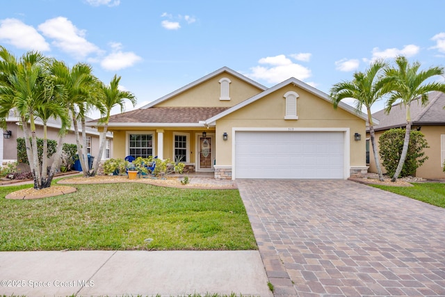 single story home with decorative driveway, stucco siding, a front yard, a garage, and stone siding