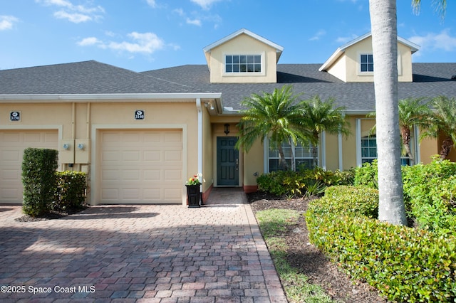 multi unit property featuring decorative driveway, roof with shingles, an attached garage, and stucco siding