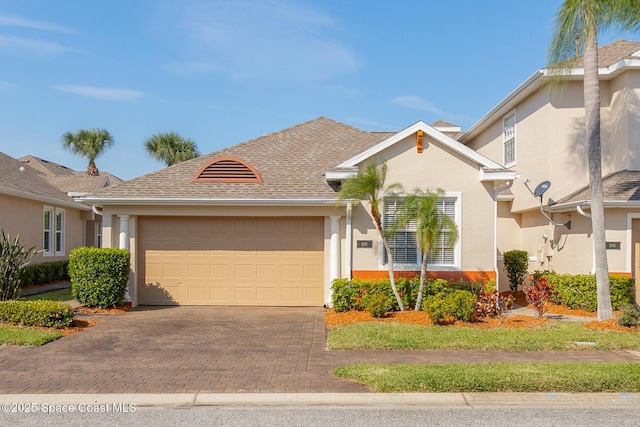 view of front facade with an attached garage, roof with shingles, decorative driveway, and stucco siding