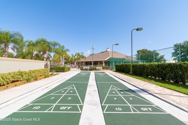 view of property's community with shuffleboard and fence