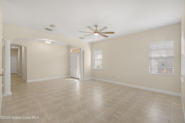 unfurnished room featuring arched walkways, decorative columns, baseboards, and ceiling fan