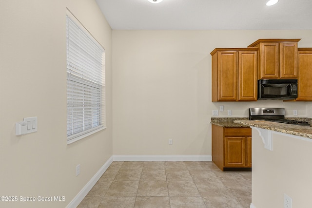 kitchen with black microwave, dark stone countertops, stainless steel range with gas cooktop, and baseboards