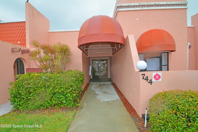 property entrance with a tile roof and stucco siding