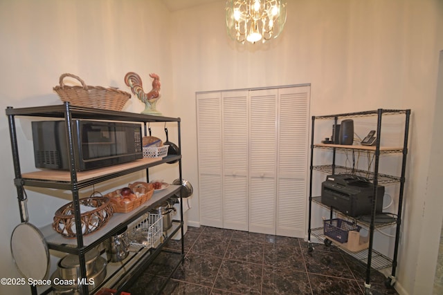 interior space with granite finish floor, an inviting chandelier, and baseboards