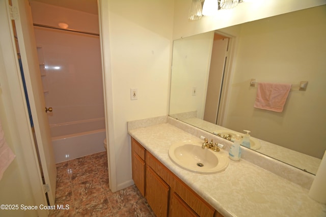 bathroom with toilet, stone finish floor, shower / tub combination, and vanity