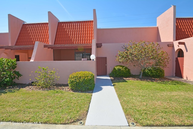 view of front of home with a tile roof, a fenced front yard, a front yard, and stucco siding