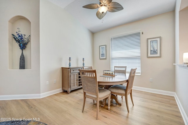 dining area featuring light wood-type flooring, baseboards, ceiling fan, and vaulted ceiling