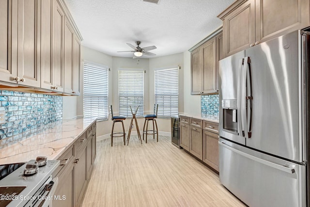 kitchen with tasteful backsplash, light stone counters, a ceiling fan, and stainless steel fridge with ice dispenser