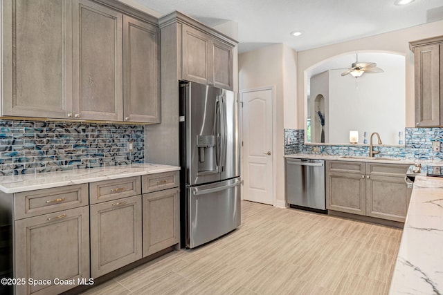 kitchen with tasteful backsplash, arched walkways, appliances with stainless steel finishes, and ceiling fan