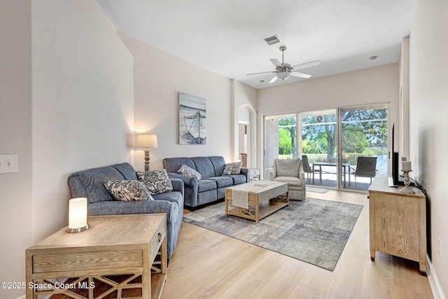 living room with visible vents, light wood-style flooring, baseboards, and ceiling fan