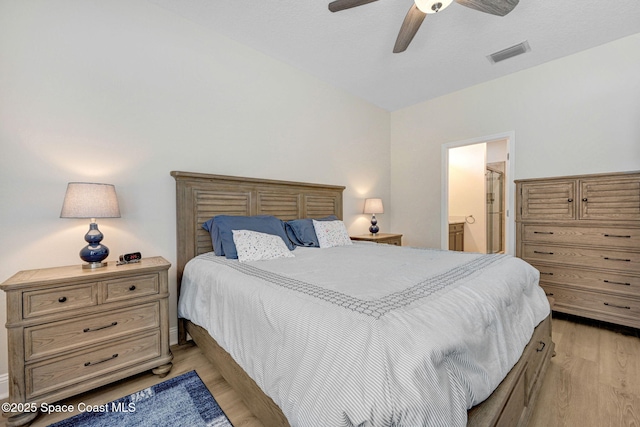 bedroom featuring ceiling fan, ensuite bath, visible vents, and light wood-type flooring