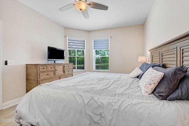 bedroom featuring ceiling fan, baseboards, and wood finished floors