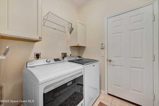 clothes washing area with washer and clothes dryer, light tile patterned floors, cabinet space, and baseboards