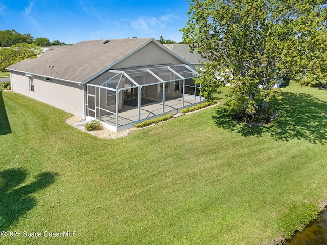 back of property with glass enclosure, a patio area, a lawn, and stucco siding