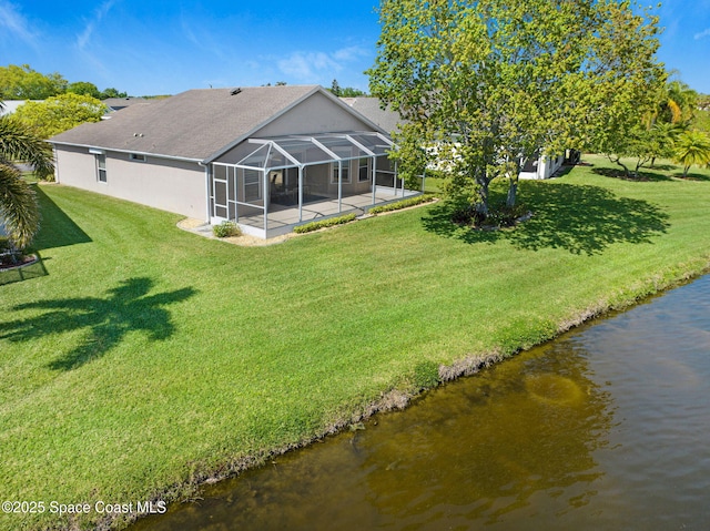 back of property with glass enclosure, stucco siding, a water view, a patio area, and a lawn