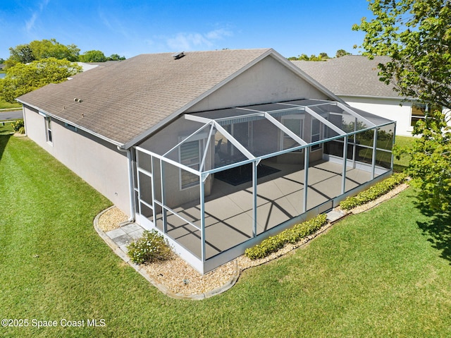 rear view of house with a shingled roof, a patio, glass enclosure, and stucco siding