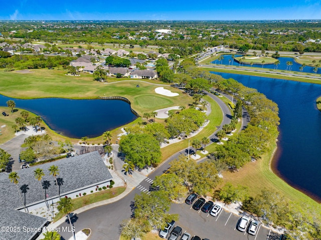 drone / aerial view with golf course view and a water view