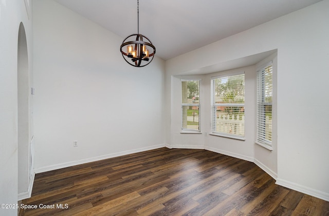 unfurnished room with a chandelier, vaulted ceiling, dark wood finished floors, and baseboards