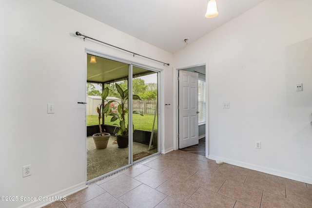 interior space with vaulted ceiling, light tile patterned floors, and baseboards